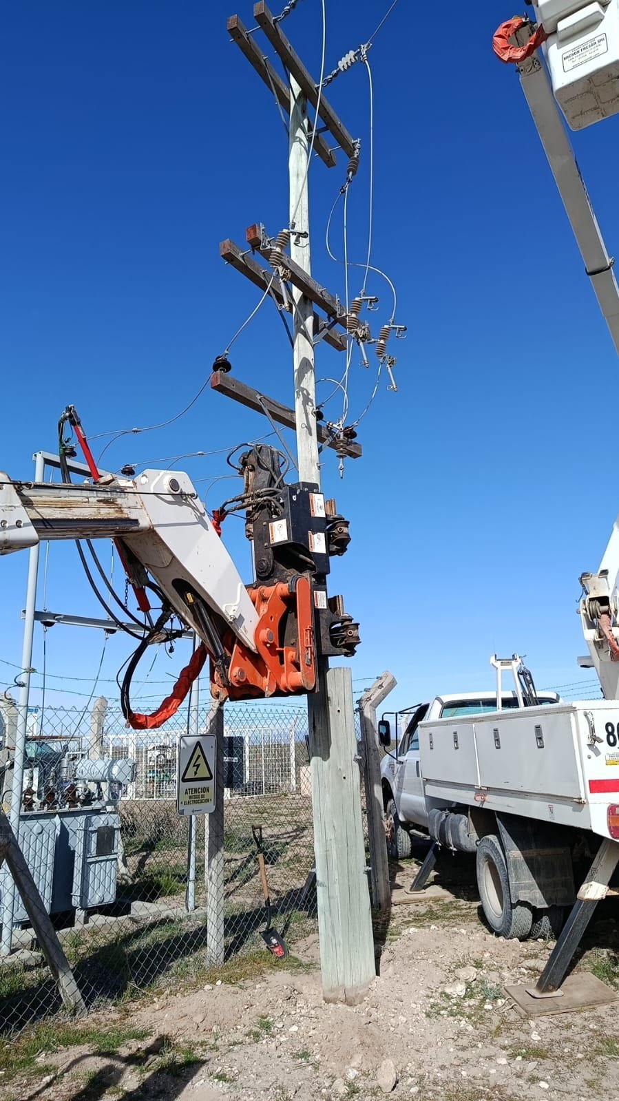 Garra posicionadora sujetando un poste junto a una estación transformadora