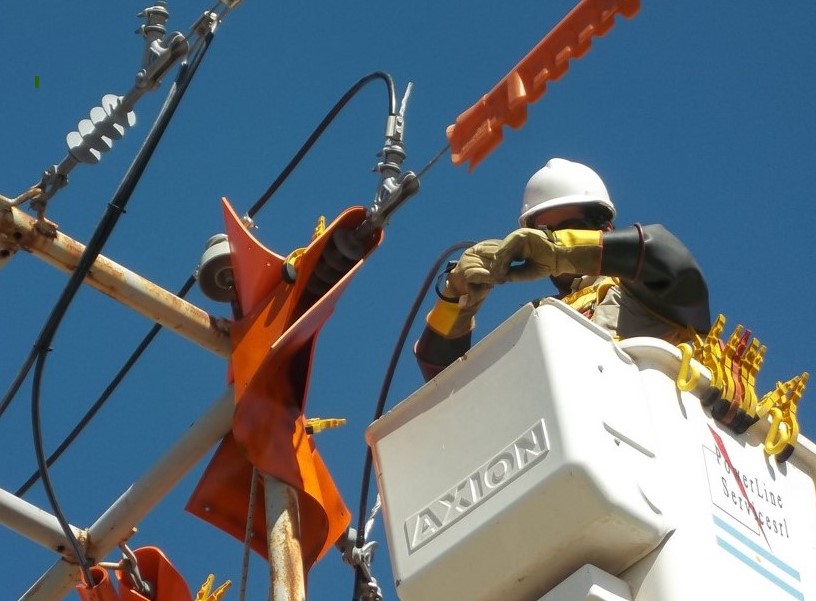 Liniero con guantes aislantes trabajando con tensión desde la barquilla del hidroelevador